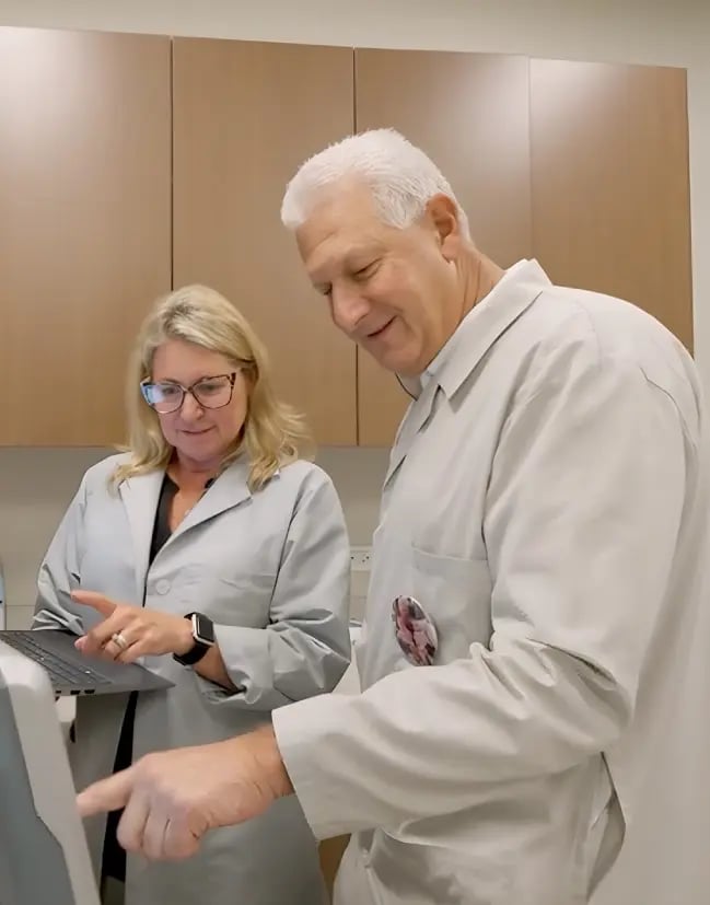 Two physicians monitoring a computer.